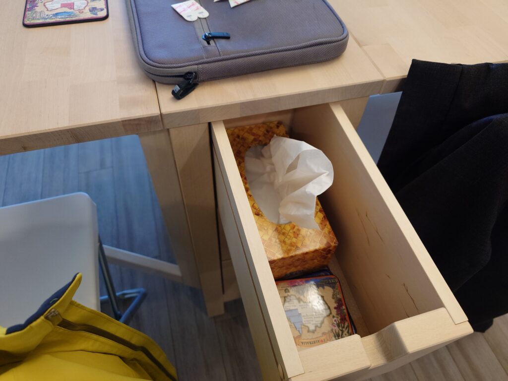 Tissues and coasters inside a table drawer.