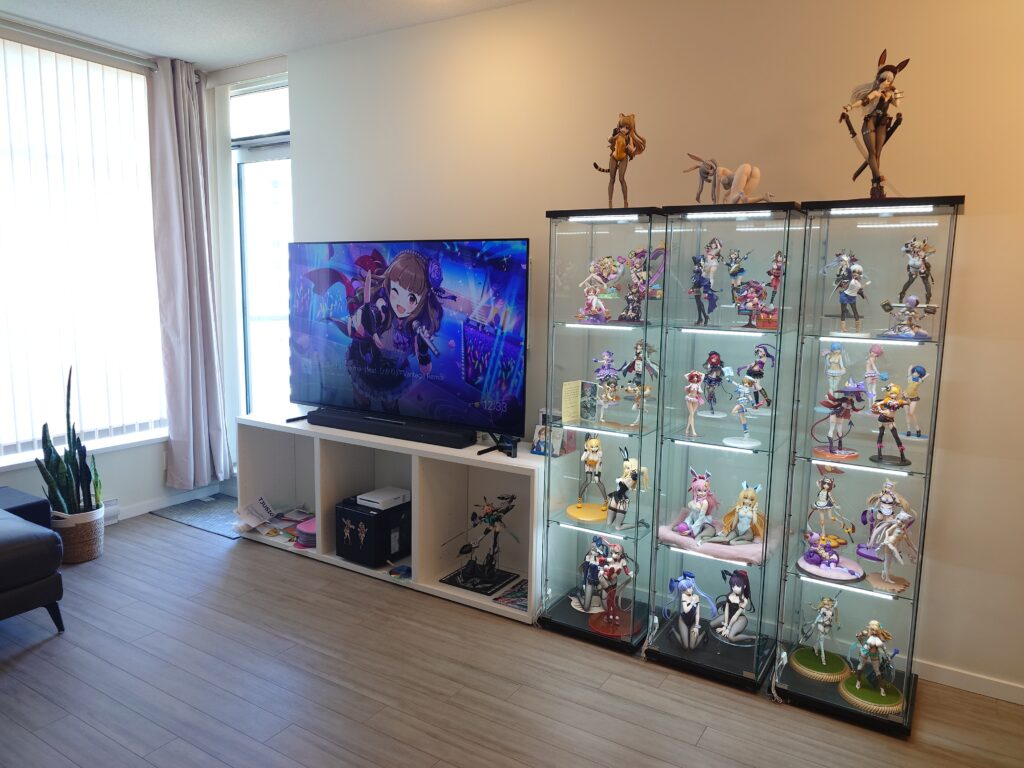 A living room area with a TV on top of a TV stand, with three display cases beside it.